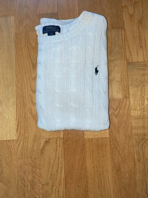 Vit kabelstickad tröja Polo Ralph Lauren - Kabelstickad vit tröja från Polo Ralph Lauren med klassisk rund halsringning och broderad logga på bröstet. Perfekt för lager på lager under höst och vinter. Priset kan diskuteras bara att höra av sig!