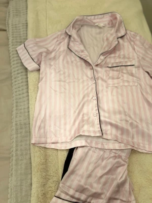  Söt tvådelad pyjamas i rosa & vitt💕 - Söt tvådelad pyjamas i rosa/vita ränder med fina svarta detaljer. Skön skjortmodell med knappar och matchande shorts med resår i midjan. Mjukt och behagligt material – perfekt för både sovning och mys hemma. 🌸✨