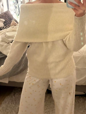 Offshoulder stickad tröja i ljus beige - Supermysig stickad offshoulder-tröja i ljus beige med bred krage som vilar över axlarna. Tröjan har långa ärmar och ribbad nederkant, perfekt för att hålla värmen under kyliga dagar. Mjuk och skön känsla, passar till jeans eller kjol.