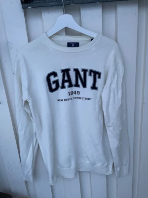Vit stickad tröja från GANT - Vit stickad tröja från GANT med broderad logga och text '1949 New Haven, Connecticut' i svart på bröstet. Rund hals och långa ärmar, ribbade muddar vid ärmslut och nederkant. Perfekt för dig som gillar klassisk college-stil. Herr modell - Stl M  Se bilder, använd men mycket fint skick!  Märke #herrmode #😍 #klader  #Vinted #uk  #mode  #loppis  #Fashion #SecondhandFinds #retro  #herrkläder  #secondhandstyle #Gant #STL M #Style #Tröjor #vinteddanmark #vintednorway #nordicbuyers #europeansellers