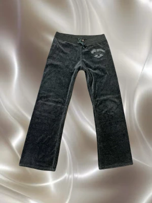 Juicy Couture mörkgrå mjukisbyxor - ÄKTA vintage Juicy Couture velour pants från tidigt 00-tal! Rakt från Paris Hilton–eran – exakt den ikoniska modellen med mjuk velour, broderad Juicy-rumpa och klassiska loggan fram. Total Y2K queen-energy. 💅✨  Storlek M (sitter som S/M). Säljer bara pga jag är 1,77 och de blev lite highwater på mig 😭 annars hade jag ALDRIG släppt dem.