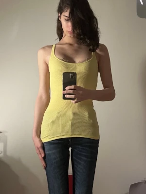 Abercrombie & Fitch yellow linen XS - Vintage, washed and well taken care of. XS but sits as S. Säljer en ljusgul ribbad linnetopp med smala axelband och figurnära passform. Toppen är ärmlös och har en enkel, stilren design som passar perfekt till jeans eller shorts. Materialet är mjukt och stretchigt för en bekväm känsla.