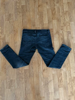 Svarta slim fit jeans från Jack & Jones - Säljer ett par svarta skinny jeans från Jack & Jones Jeans Intelligence. Jeansen har en tight passform, klassisk femficksdesign och är tillverkade i stretchig bomullsmix för extra komfort. Snyggt tvättade detaljer och normal midja.W29 L30