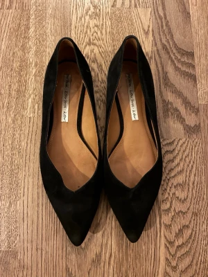 Svarta pumps med spetsig tå, 1 cm klack - Säljer ett par eleganta svarta pumps från & Other Stories med spetsig tå. Skorna är tillverkade i mocka och har en klassisk siluett som ger en stilren look. Perfekta för dig som gillar tidlös design och vill ha ett par snygga skor till garderoben. 