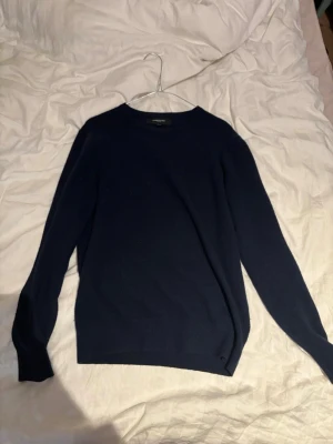 Mörkblå Kashmir tröja från Lawrence grey  - En enkel och stilren mörkblå kashmir tröja från Lawrence grey. Tröjan har rund halsringning och långa ärmar. Perfekt att slänga på sig när det är lite kyligare ute. Passar till det mesta och är ett måste i garderoben.