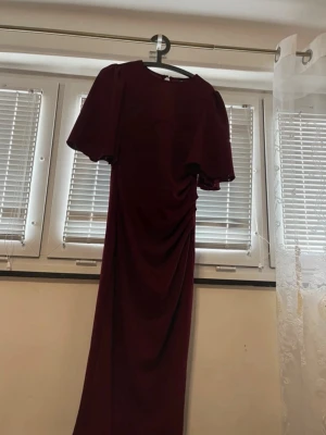 Burgundy Ruched Midi Dress – Elegant & Fitted - Elegant burgundy/maroon midi dress with a flattering fitted silhouette. Features short sleeves and a ruched detail on the side that enhances the shape beautifully. Soft, stretchy fabric that is comfortable to wear and perfect for both casual occasions and evening events. Gently used and in good condition. Ideal for parties, dinners, weddings, or special occasions. Color: Burgundy / Wine red Length: Midi Style: Fitted, ruched, elegant 