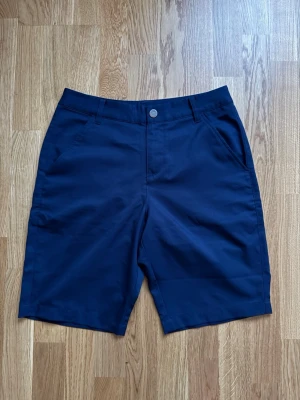Blå golfshorts från Puma, storlek 28 - Blåa supersköna golfshorts från Puma med klassisk design och  logga baktill. Perfekt att ha dem varmaste rundorna.🏌️‍♂️⛳️