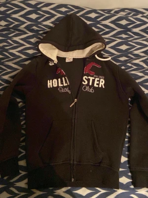 Hollister hoodie XS - Snygg och trendig hollister hoodie, bra skick förutom att det kan förekomma små fläckar, men dessa märks inte i det stora hela, kolla gärna in mina andra annonser. Storlek 176 cm, men mindre i storleken.