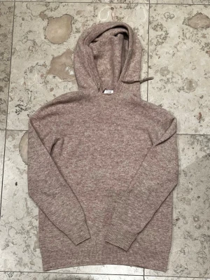 Kashmir Hoodie från Rogé Clothing  - Säljer en snygg kashmir hoodie från Rogé clothing i en beige/brun färg. Hoodien har slitits upp vid luvan (Syns på bild 2) därav det låga priset! Annars i bra skick!
