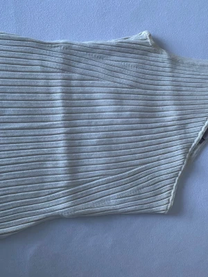 Vit ribbad bandeau topp H&M - Säljer en vit bandeau topp från H&M i storlek M. Toppen är ribbad och har en enkel, stilren design utan axelband. Perfekt för varma dagar eller som layering-piece. Materialet är mjukt och stretchigt för en bekväm passform.