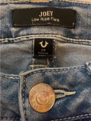 True Religion Joey W25 - Säljer ett par AVKLIPPTA ljusblå True Religion Joey jeans med låg midja och flare-ben. Jag är 162 cm och de är lite korta för mig:) förutom att de är avklippta är dem i ganska bra skick. 