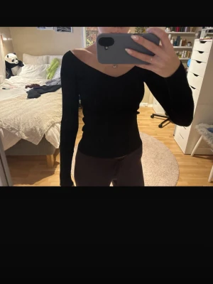 Svart ribbad topp från H&M XS - Säljer en svart ribbad topp från H&M i storlek XS. Toppen har lång ärm, v-ringad urringning och är figurnära i modellen. Materialet är stretchigt och mjukt, perfekt till många olika looks. Enkel och stilren design som är lätt att matcha.