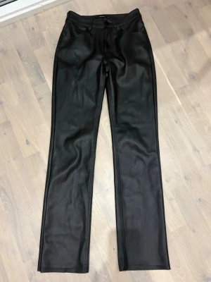 Svarta raka byxor i skinnimitation BikBok - Säljer ett par svarta byxor från BikBok i skinnimitation. De har raka ben, låg midja och klassisk femficksdesign. Snyggt minimalistiska och passar perfekt till en trendig look. Stängs med knapp och dragkedja framtill. Uppsprättande nertill