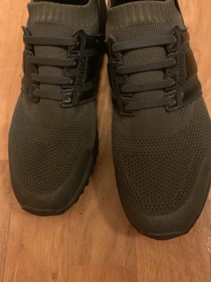 Svarta sneakers från Björn Borg - Snygga svarta sneakers från Björn Borg med stickad ovandel och elastisk mudd runt ankeln. Skorna har svarta detaljer och snörning framtill samt tydlig logga på sidan och hälen. Perfekta för en sportig och modern look.