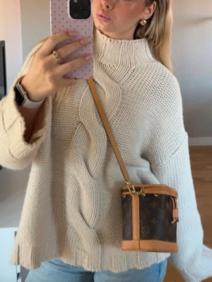 Beige stickad tröja med polo - Säljer en chunky beige stickad tröja med hög hals och snyggt flätmönster framtill. Tröjan har lång ärm och en loose fit som ger en avslappnad vibe. Perfekt att slänga på sig till jeans för en enkel men stilren look. Knappt använd💕
