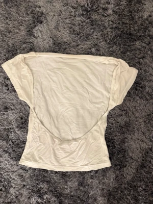 Vit topp med öppen rygg  - Säljer en enkel och stilren vit topp i mjukt bomullstyg. Den är öppen i rygggen och väldigt bekväm. Inga skador!