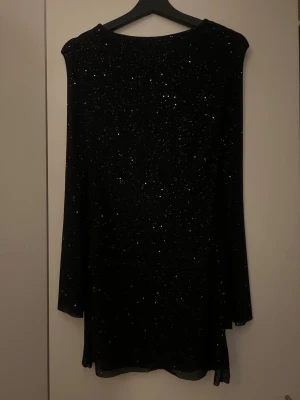 Svart glittrig kortklänning med öppen rygg - Festlig svart glitter klänning med öppen rygg, storlek s