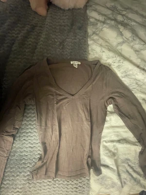 Brun långärmad topp från Amisu - En basic brun långärmad topp från Amisu med v-ringning. Toppen är i mjukt och tunt material, perfekt att styla med jeans eller kjol. Enkel och stilren design utan mönster eller extra detaljer.