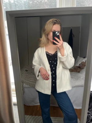 Vit oversized kavaj med knapp - Säljer en vit tjockare kavaj med en enkel knapp framtill. Jackan har en rak passform och långa ärmar som kan vikas upp för en mer avslappnad look. Perfekt att slänga över en topp eller hoodie för en clean och stilren vibe.