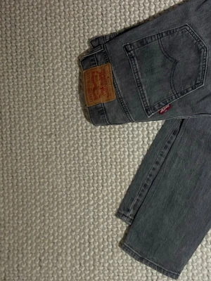 Levi's 512 grå jeans straight fit  - Säljer ett par klassiska Levi's 512 jeans i snygg grå tvätt. De har rak passform, fem fickor och den ikoniska röda Levi's-lappen bak. Jeansen är i ett mjukt jeanstyg och passar perfekt till en avslappnad stil.