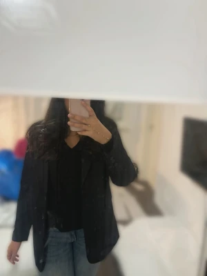 Svart kavaj i klassisk modell - Säljer en svart kavaj med klassisk passform och knappar vid ärmslut. Perfekt att slänga över en t-shirt eller blus för en clean look. Tidlös design som funkar till det mesta och ger en snygg siluett.