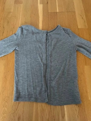 Grå kofta - En grå kofta från Gina med grå knappar som man kan knäppa upp 