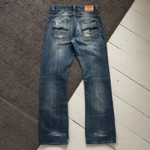 Mörkblåa Nudie Regular Alf Premium Selvedge Jeans - Riktigt snygga Nudie Jeans i Regular Alf, Premium Selvedge! | W30 L32  | Riktigt fint skick, finns snygga slitningar, och där nere där man cuffar jeansen är det även slitning/hål. | Midja: 39-42cm (Stretch) längd: 106 | Tydliga fades och allmänt unika. | Skriv vid frågor, pris ej hugget i sten! 