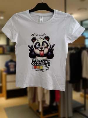 Vit t-shirt med panda och text - Vit t-shirt med tryck av en tecknad panda som gör peace-tecken och texten 'Sarcastic comments loading...'. T-shirten har rund hals, korta ärmar och är i mjuk bomull. Perfekt för dig som gillar humor och coola prints.