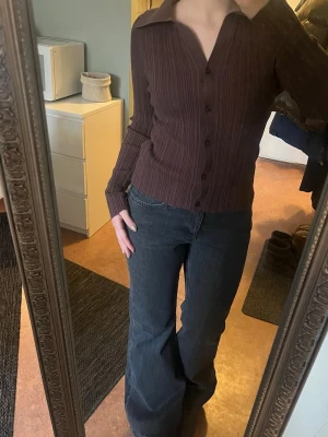 Brun ribbad kofta från NA-KD - Säljer en brun ribbad kofta/topp/tröja från NA-KD i storlek M. Tröjan har lång ärm, klassisk krage och knäppning framtill. Materialet är mjukt och stretchigt. Storlek m men passar även mig som är xs/s. Kragen ser lite ljusare ut på bild men fortfarande fin att använda.