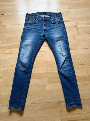 Lee jeans slim - Snygga blå slim jeans från Lee.                        Klassisk jeansmodell med en smal passform och stretch. Defekt på vänstra knäet därför billigare pris. Storleken är W31 L32 