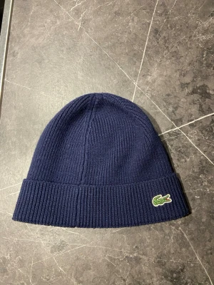Lacoste mössa  - Fet Lacoste mössa, perfekt för de kalla dagarna - undrar du över något är de bara att skriva PM🙌. Pris kan diskuteras.