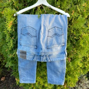Replay Anbass ljusblå jeans, stl 28 - Säljer ett par Replay Anbass jeans i ljusblå tvätt med snygga slitningar och klassiska bakfickor med broderad detalj. Modellen har normal passform och raka ben. Jeansen har dragkedja och knapp framtill samt Replay-logga på fickan.