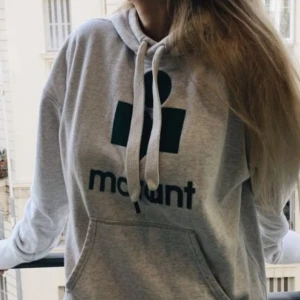 Grå hoodie från Isabel Marant - Snygg grå hoodie från Isabel Marant med svart logga framtill. Nypris 2300, Tröjan har huva med snörning, stor magficka och ribbade muddar. Perfekt för hösten, knappt använt. Storlek s, men skulle säga att den passar xs-m