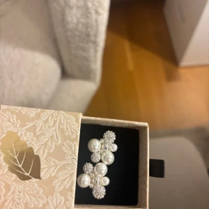 Glittriga örhängen med pärlor  - Säljer ett par örhängen med vita pärlor och gnistrande strassbollar i silver. Perfekta för dig som vill sticka ut med lite extra bling! Helt nya oanvända 💞ny pris 600