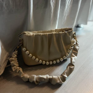 Beige väska  - Supersöt beige väska. Förvånansvärt rymlig och jättebra kvalité. Finns även ett tillhörande långt axelband