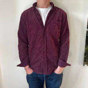 Vinröd Manchester Skjorta - Manchester skjorta från These Glory Days. Skick - 10/10. Nypris - Ca 1000kr. Mitt pris - 399kr. Storlek S men passar XS. Personen på bilden är 175cm.