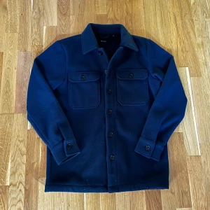  Matinique Overshirt - Snygg mörkblå overshirt från Matinique i storlek XS. Jackan har klassisk krage, två stora bröstfickor med knappar och stängs med knappar framtill. Tillverkad i ett mjukt ullmaterial som ger en clean och stilren look. Hör av dig vid funderingar! Mvh Carl