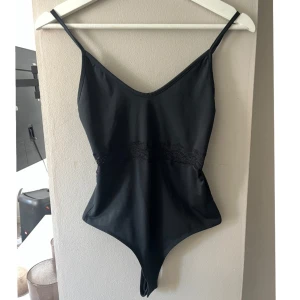 Svart body med spetsdetalj - Snygg svart body från Bikbok med smala axelband och v-ringning. Bra skick☺️