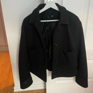 Svart kappa - Kort kappa från Lager 157. Mycket fint skick, inga hål eller defekter. 2 fickor på sidan och alla knappar sitter kvar. Storlek S och är normal i storleken.