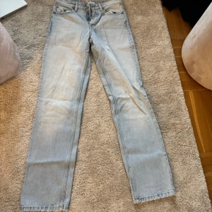 Ljusblå raka jeans - Säljer ett par ljusblå jeans med klassisk femficksdesign och raka ben. Jeansen har en enkel look och är tillverkade i denim. Perfekta för dig som gillar en clean och avslappnad stil.
