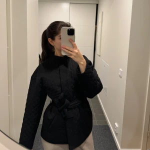 Svart quiltad jacka med bälte - Säljer en svart quiltad jacka med knappar framtill och avtagbart bälte i midjan. Använd fåtal gånger och inga defekter. Säljer då den inte kommer till användning längre 💕