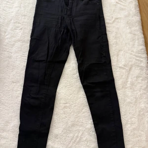 Svarta skinny jeans - Svarta jeans med smal passform och klassisk femficksdesign. Byxorna har en tight siluett hela vägen ner och är tillverkade i ett stretchigt jeanstyg som sitter snyggt. Perfekta för dig som gillar en stilren och enkel look.