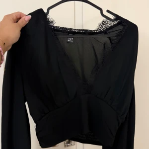 Svart omlottopp med spetsdetaljer - Jättefin topp/blus för mer finare tillfällen. V ringad och croppad.