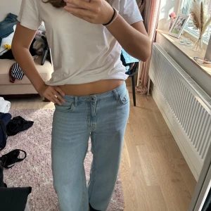 Ljusblåa wide jeans med låg midja - Säljer ett par ljusblå jeans med låg midja och breda ben. Jeansen har klassisk femficksdesign och raka bakfickor. Perfekta för dig som gillar en avslappnad och trendig look. Materialet är mjukt denim som sitter skönt hela dagen.