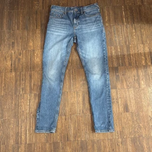 Blå jeans från Tommy Hilfiger, stl 164 - Snygga blå jeans från Tommy Hilfiger i klassisk modell med raka ben.  detaljer som Hilfiger-logga på bakfickan och läderpatch i midjan. Perfekta för en avslappnad och trendig look.