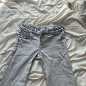 Ljusgrå bootcut jeans - Snygga ljusgrå jeans med bootcut passform och klassisk femficksdesign. Jeansen har bälteshällor, dragkedjegylf och är tillverkade i mjukt jeanstyg. Perfekta för dig som gillar en avslappnad men trendig look.