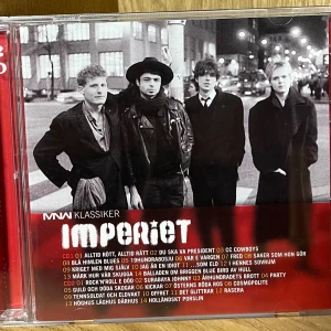 Imperiet - MNW Klassiker (2CD) - Dubbel-CD med Imperiets största hits i MNW Klassiker-serien. Omslaget och fodralet är i fint skick, med endast mindre spår av hantering. Perfekt för samlare eller fans av svensk rock.