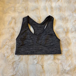Mörkgrå sportig linnetopp XS/S - Säljer en mörkgrå, melerad sportig linnetopp. Toppen har brottarrygg och är tillverkad i en mjuk blandning av polyester, nylon och elastan. Perfekt för träning och har en tight passform som sitter skönt på kroppen.