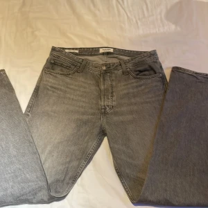 Grå loose fit jeans Jack & Jones - Säljer ett par grå loose fit jeans från Jack & Jones, modell Chris. Jeansen har klassisk femficksdesign, raka ben och är tillverkade i mjukt denimtyg. Perfekta för dig som gillar en avslappnad och trendig look.