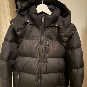 Svart pufferjacka Polo Ralph Lauren M - Svart pufferjacka från Polo Ralph Lauren i storlek M. Jackan är i fint skick och har nästan bara hängt i garderoben.